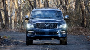 A blue 2022 Infiniti QX80 is parked outside in the woods.