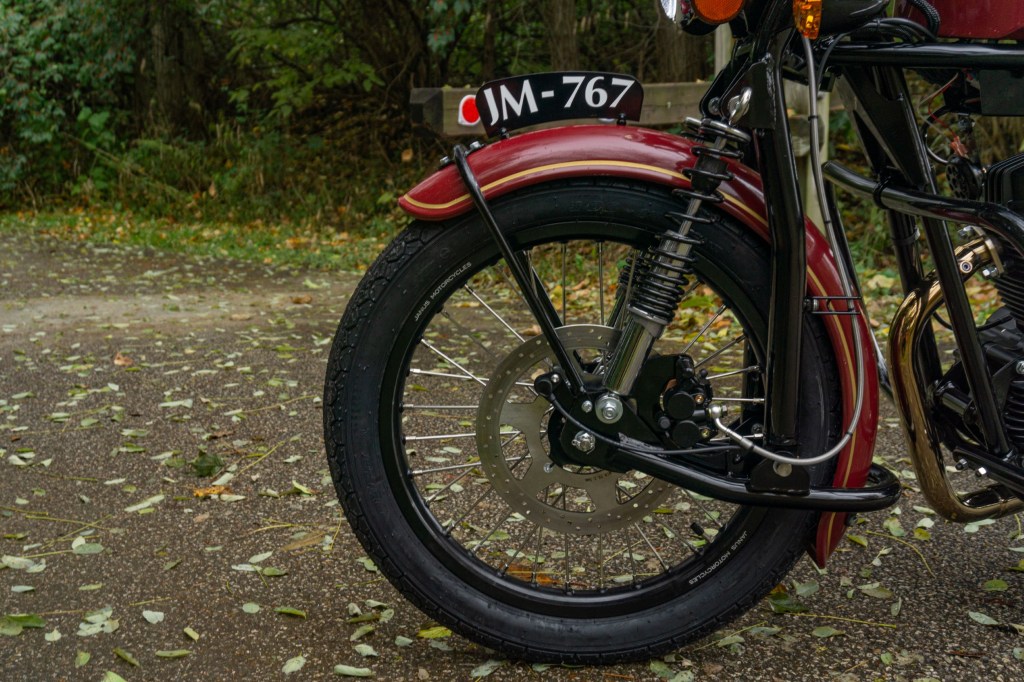 A close-up side view of a red-and-chrome 2022 Janus Halcyon 250's leading-link fork and front disc brake