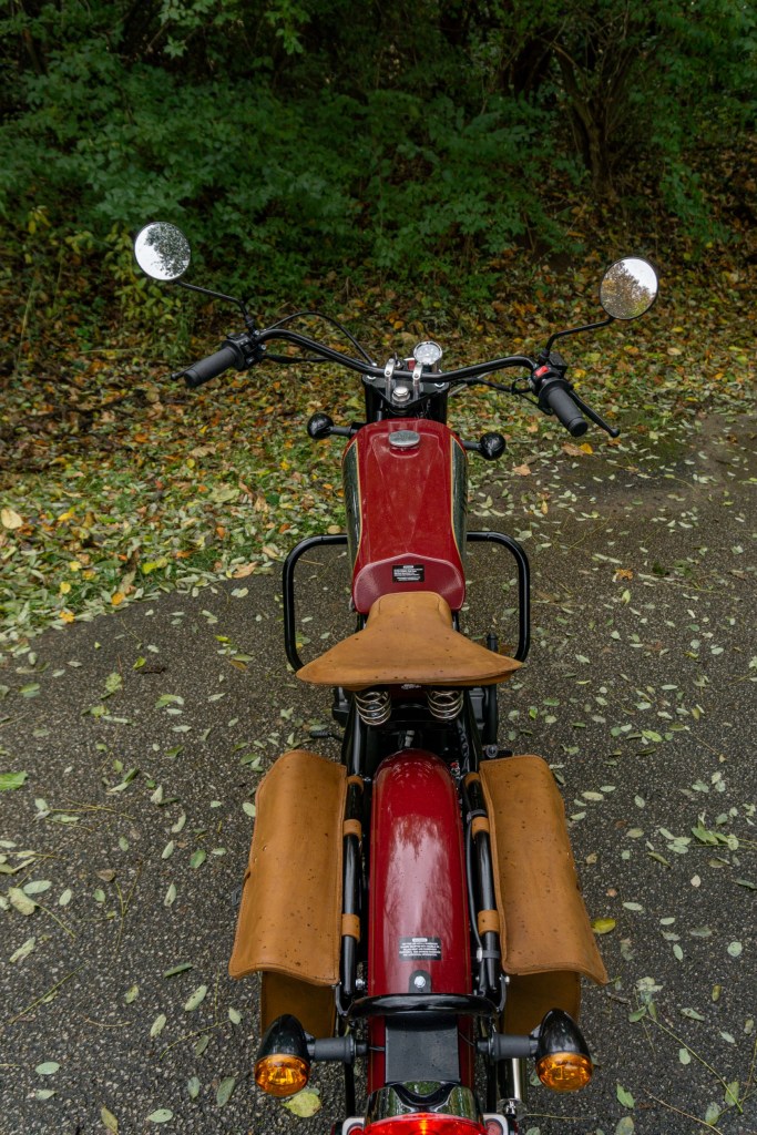 The overhead rear view of a red-and-chrome 2022 Janus Halcyon 250 on a forest path