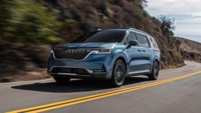 A blue 2022 Kia Carnival minivan driving on a road, it's been recalled