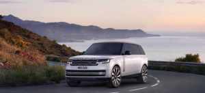 A silver 2022 Land Rover Range Rover parked in front of mountains and a large body of water