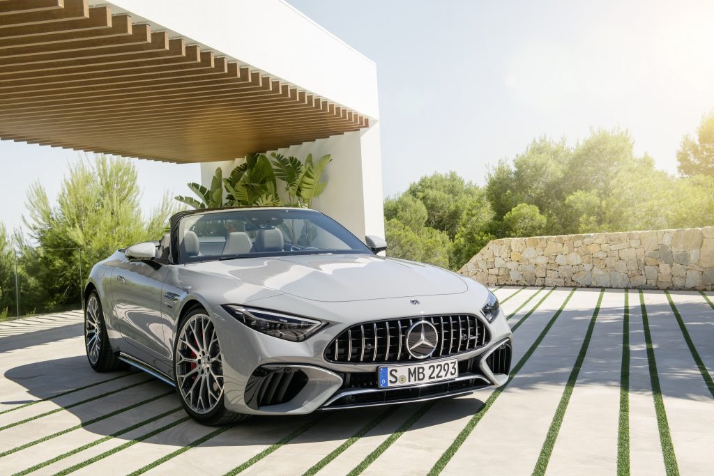 The front 3/4 view of a gray 2022 Mercedes-AMG SL 55 Roadster next to a tree-surrounded white building
