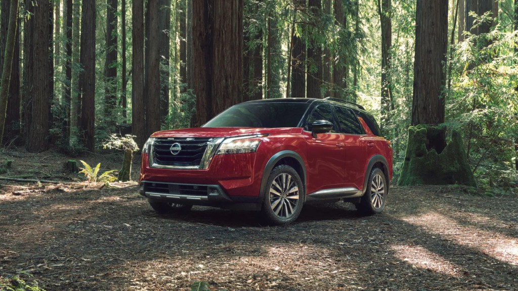 A red 2022 Nissan Pathfinder parked in a forest, here's the features, price, and specs.