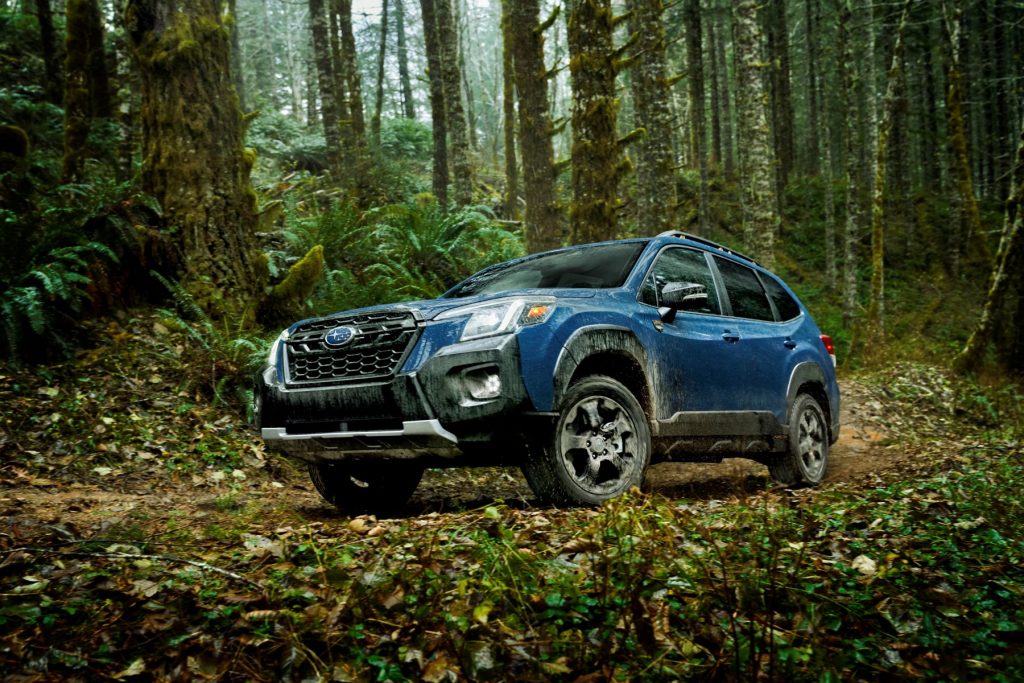 The 2022 Subaru Forester Wilderness compact SUV with a light blue teal color option parked within a wild forest.