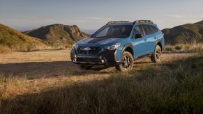A blue 2022 Subaru Outback Wilderness wagon shot on a dirt road from the 3/4 angle