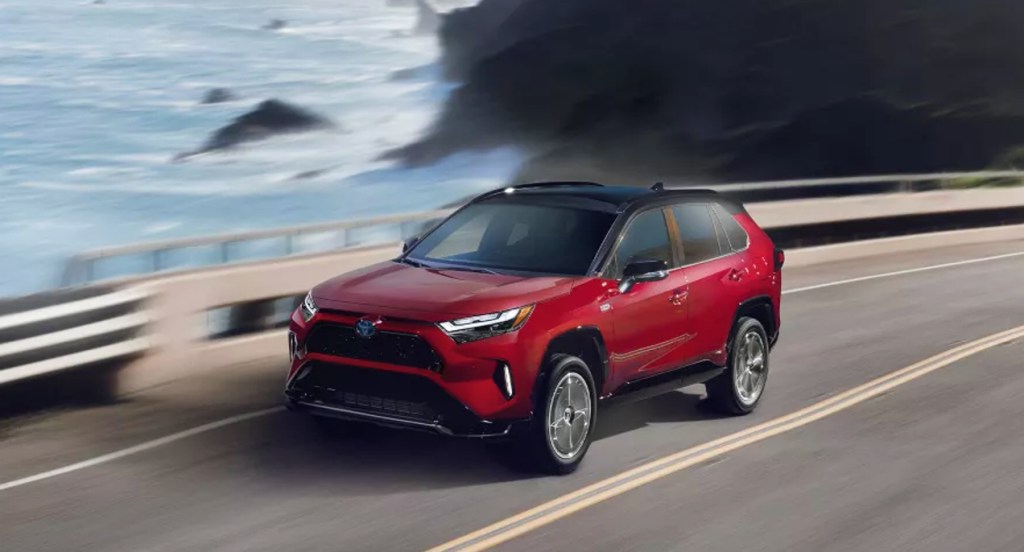 A red Toyota RAV4 Prime is driving on the road.