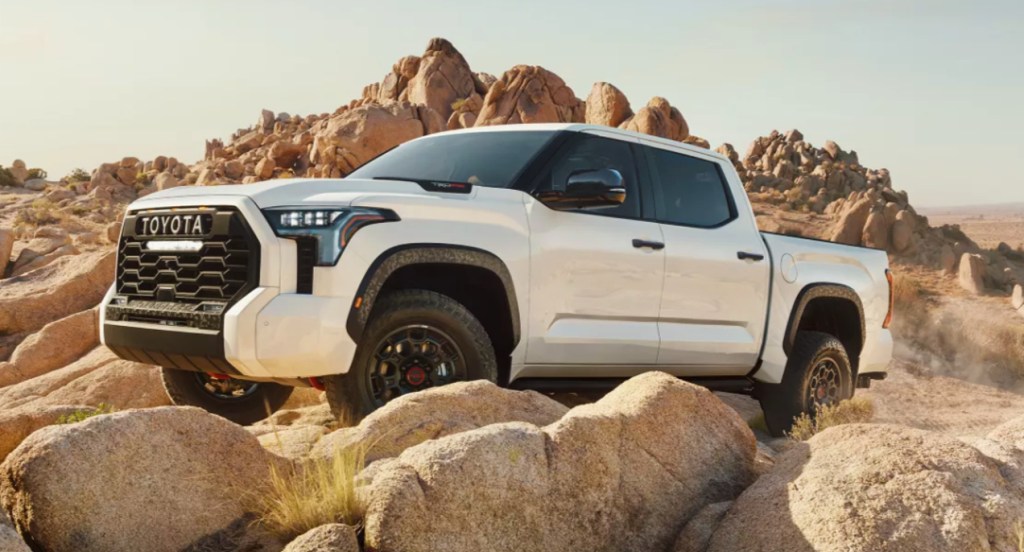 A white 2022 Toyota Tundra is driving on rocky terrain. 
