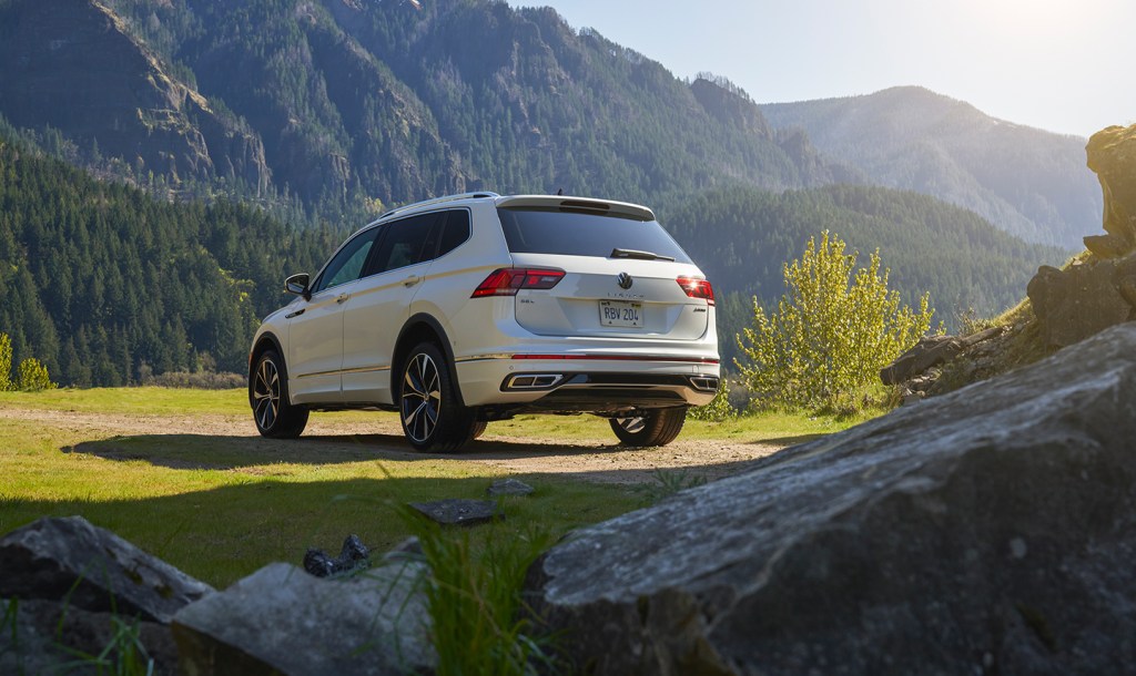 A white 2022 Volkswagen Tiguan sits on grass with a mountainous background
