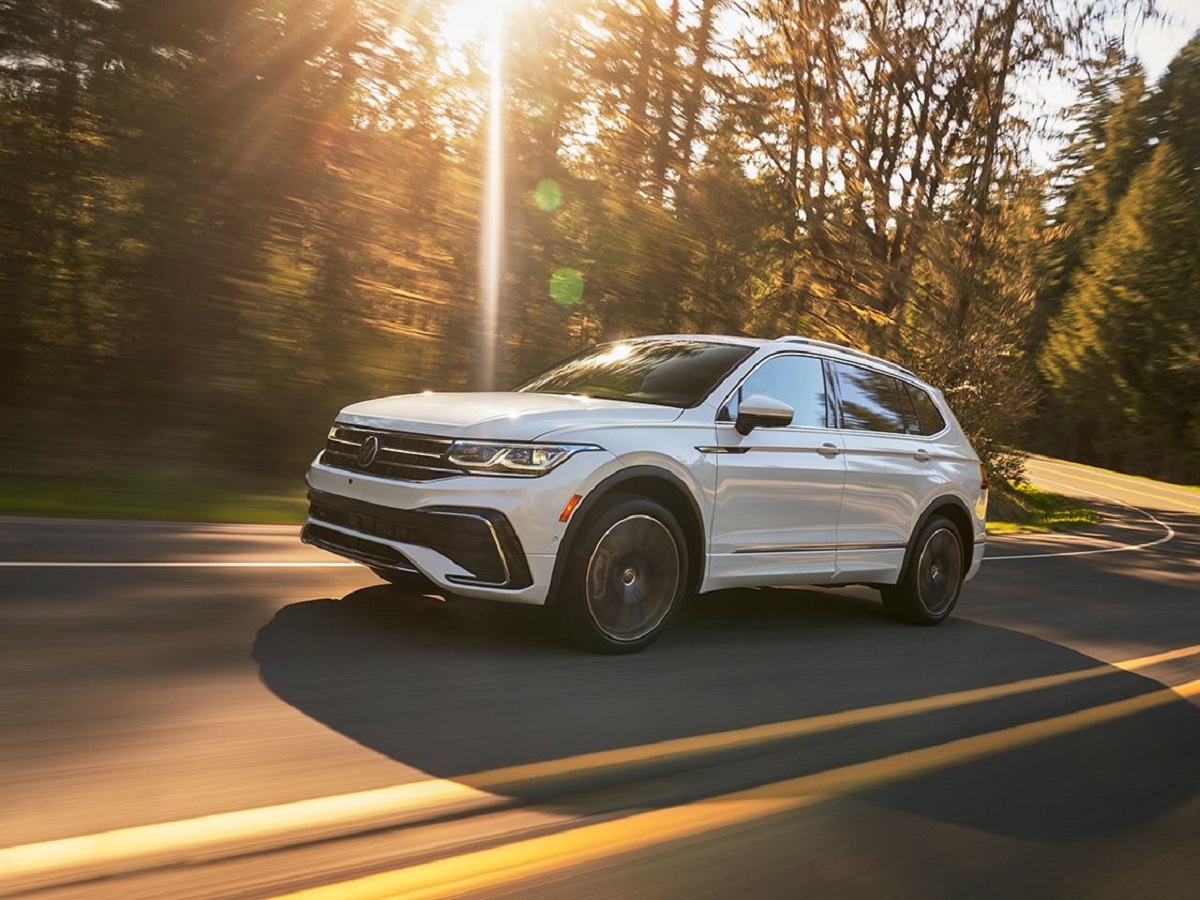 A white 2022 Volkswagen Tiguan driving down a sunny road.