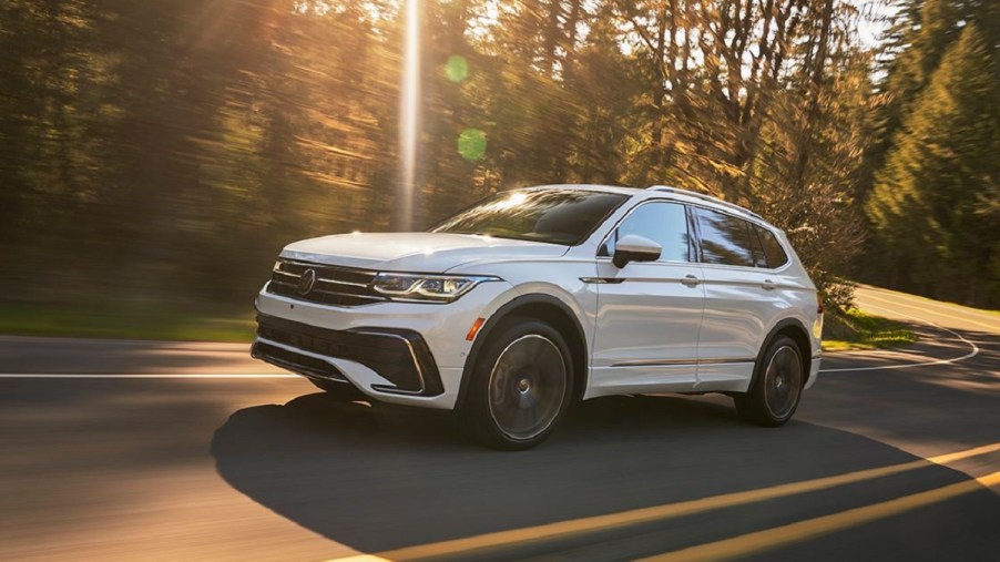 A white 2022 Volkswagen Tiguan driving down a sunny road.