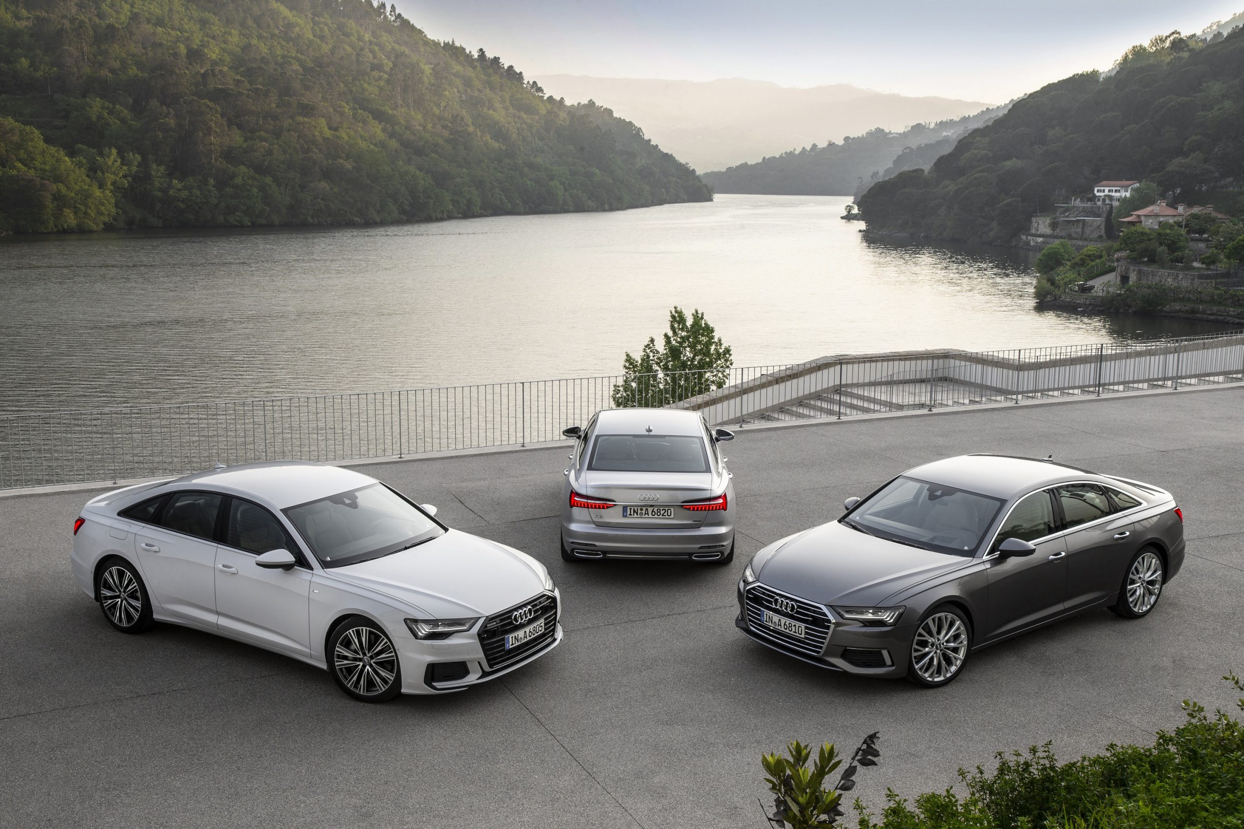 A trio of silver and grey Audi A6 sedans by a lake
