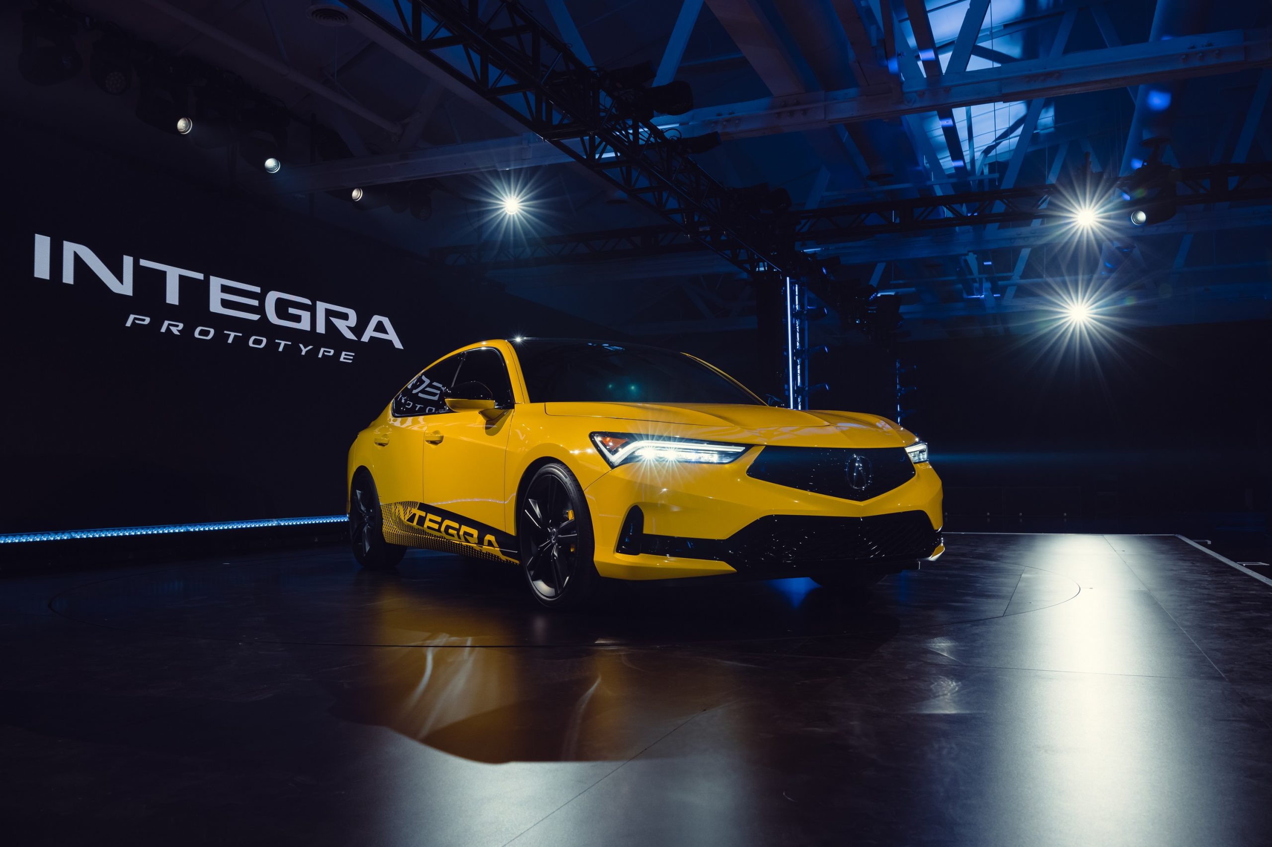 A yellow 2023 Acura Integra on stage at its debut in Los Angeles
