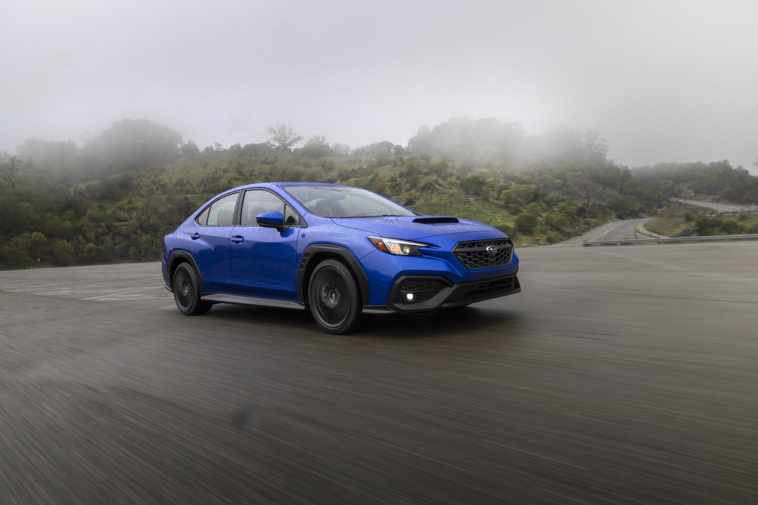A Rally Blue 2022 Subaru WRX, which swayed Doug DeMuro's opinion, shot from the front 3/4 in the rain
