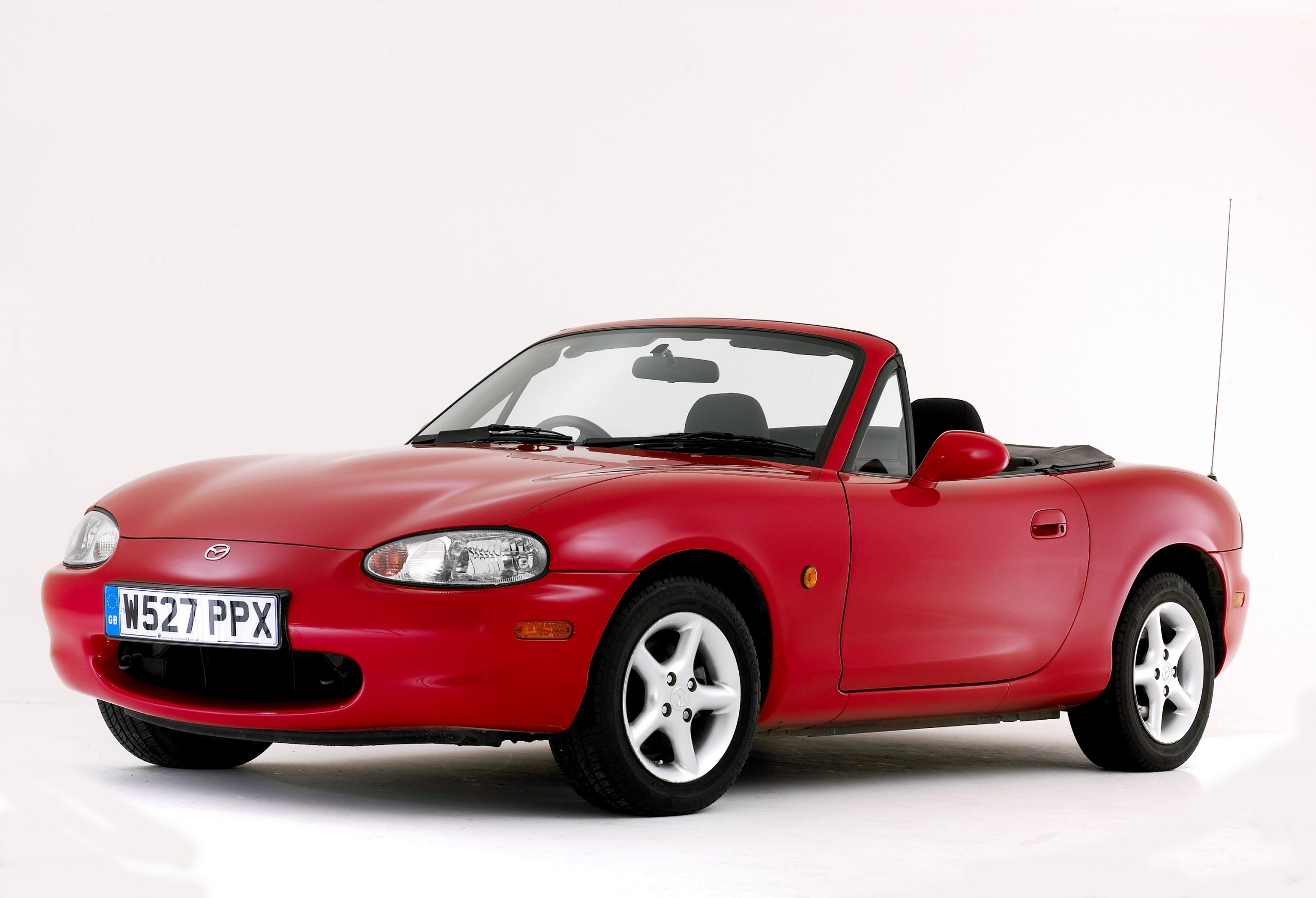 A red convertible Mazda Miata shot from the front 3/4 in a photo studio