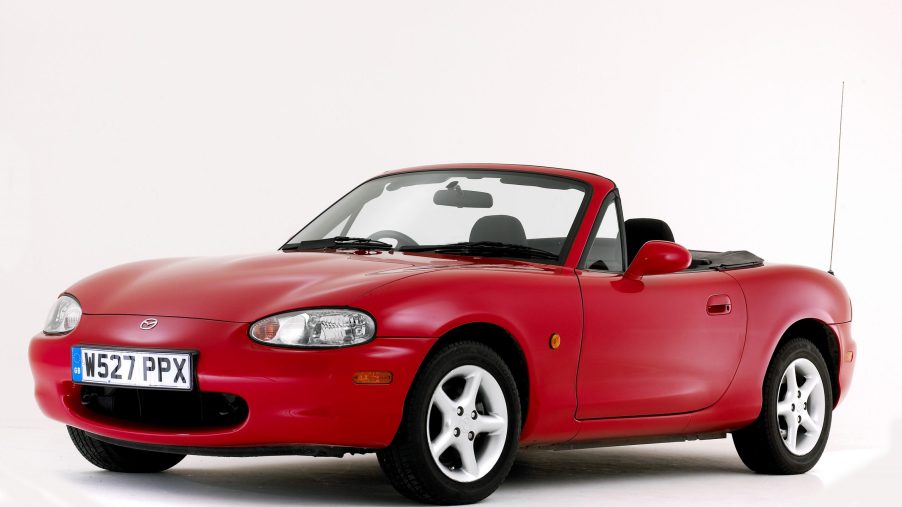 A red convertible Mazda Miata shot from the front 3/4 in a photo studio
