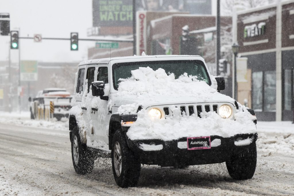 A white Jeep Wrangler driving through the snow in Denver, Colorado, it's better than electric vehicles (EVs) in the snow