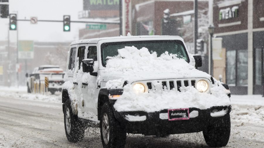 A white Jeep Wrangler driving through the snow in Denver, Colorado