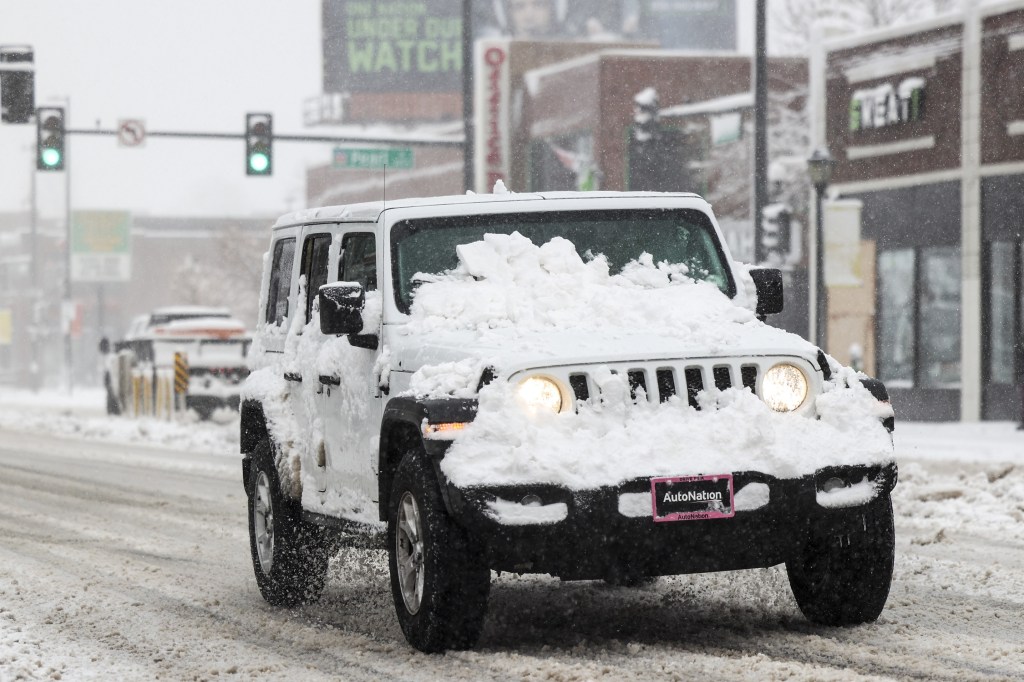 A white Jeep Wrangler covered in snow, here are some tips for driving in winter weather.