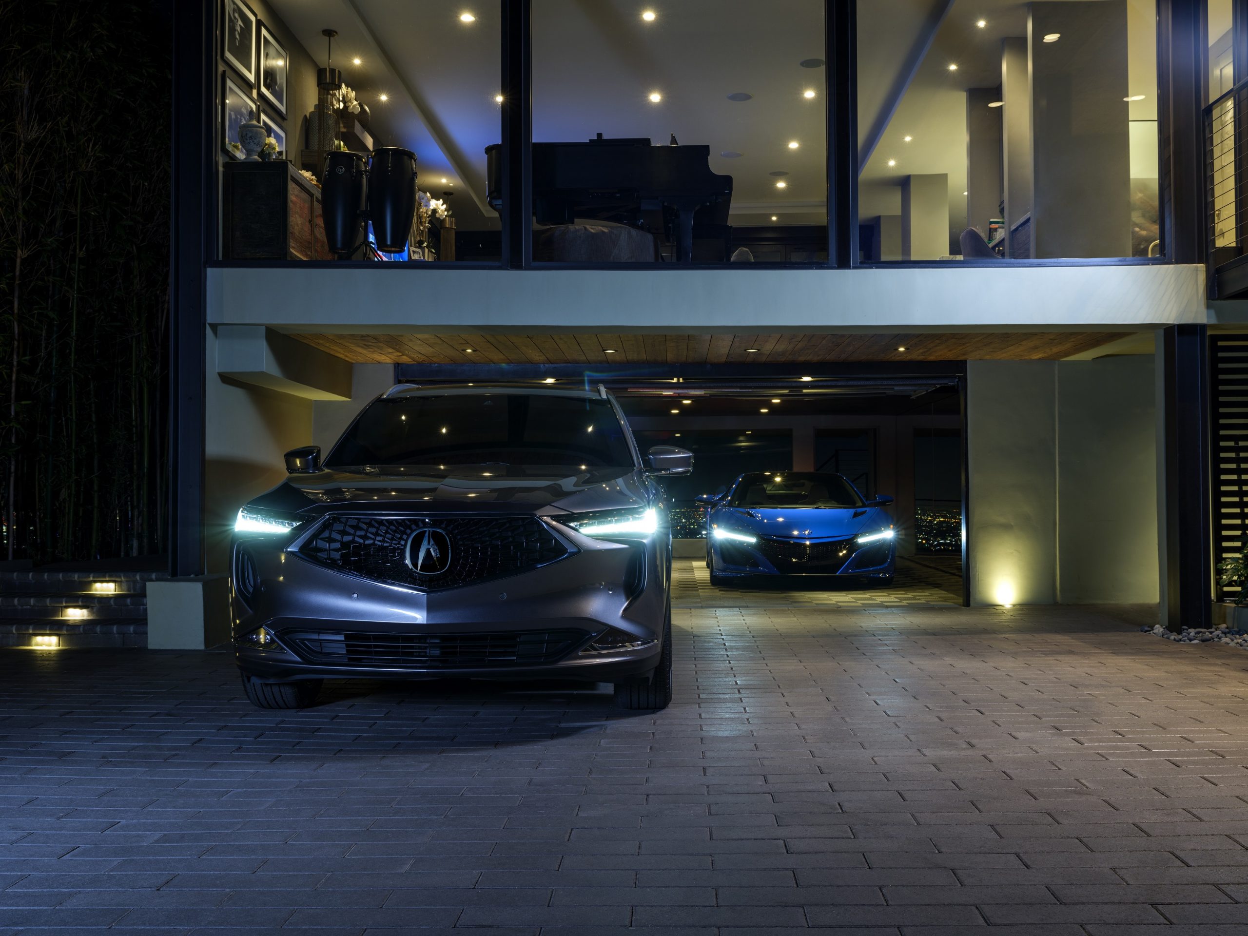 A grey Acura MDX hybrid and an Acura NSX shot at night