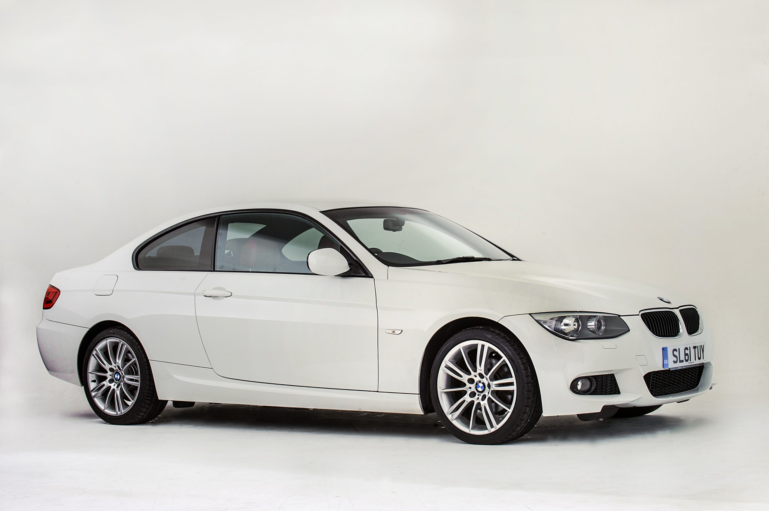A white 3 Series coupe shot in a photo booth from the 3/4 angle