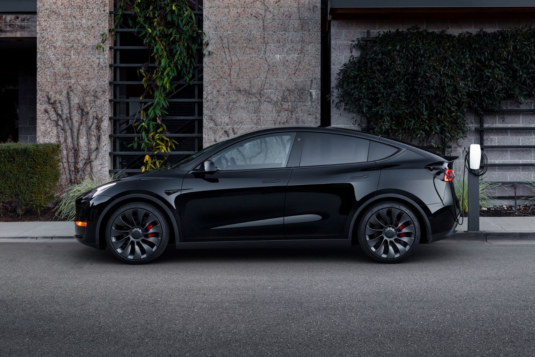 Solid Black 2022 Tesla Model Y charging at a charging station