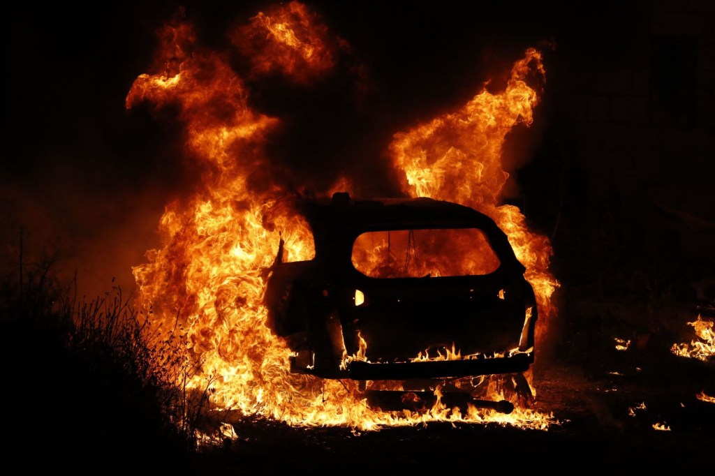 Burning flames shooting out of a car that's on fire