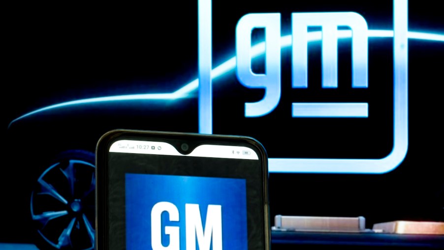 GM logos displayed on a smartphone and in the background
