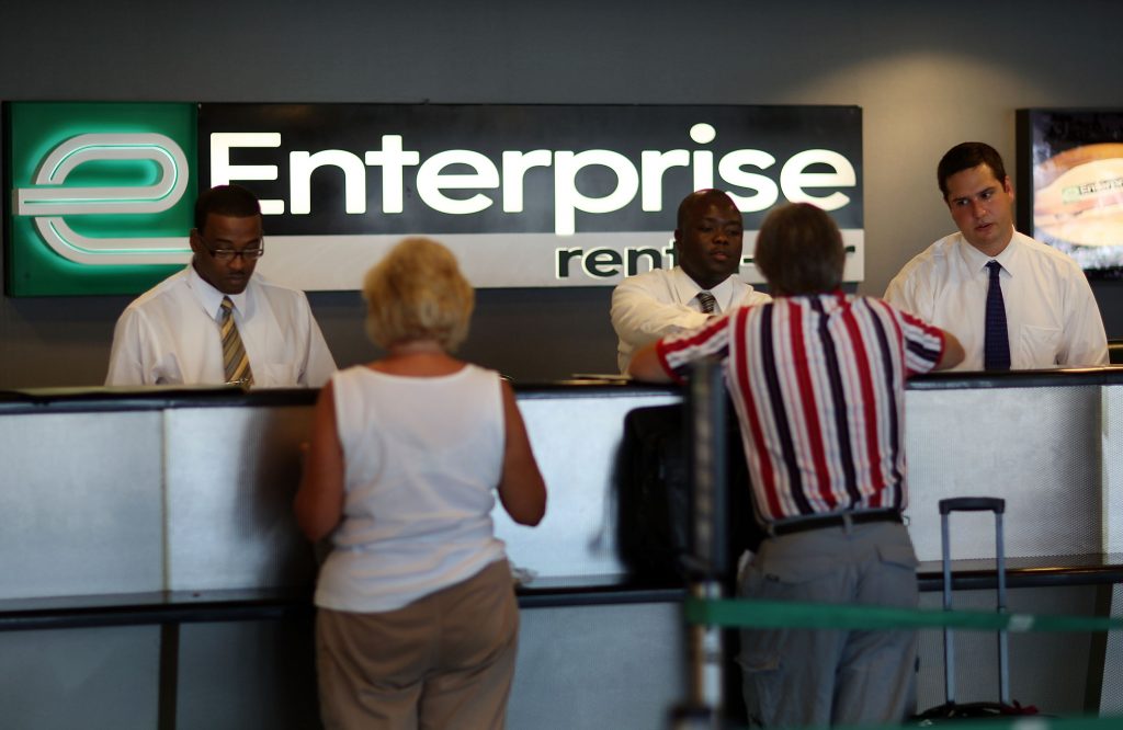 Customer service representatives assist customers at the Enterprise car rental counter. 