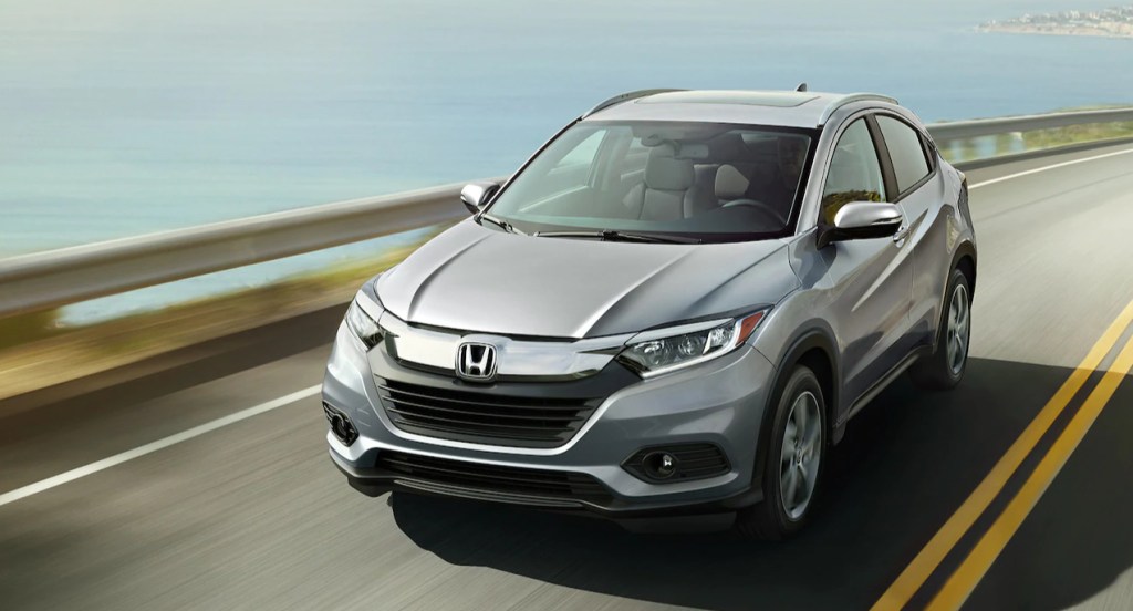 A silver Honda HR-V is driving down the road. 