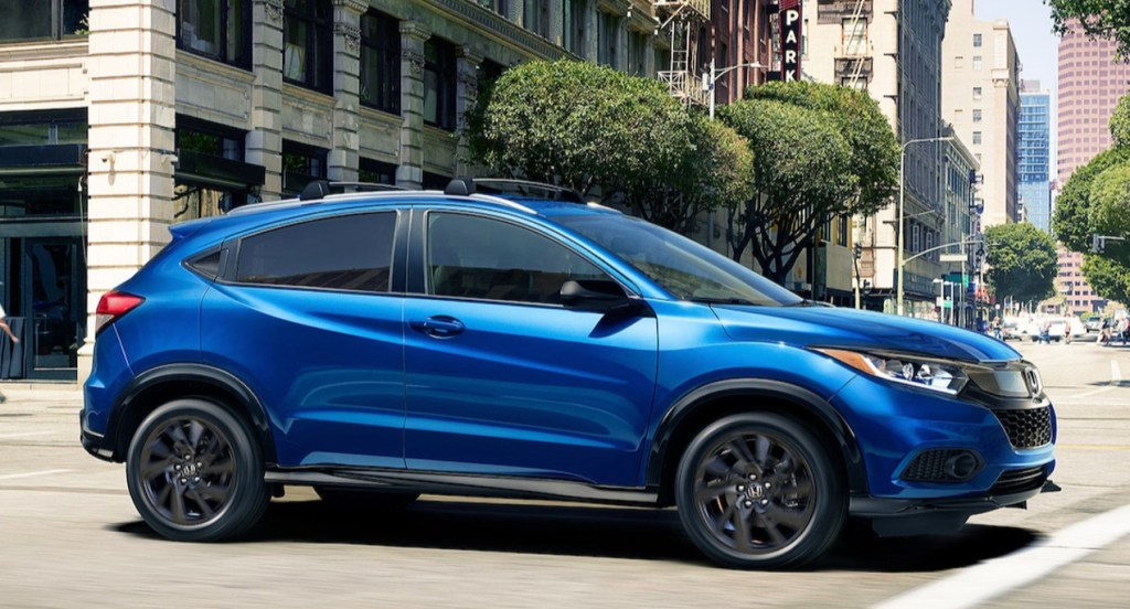 A blue Honda HR-V is driving down the road. 