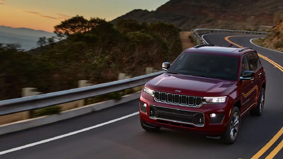 A red 2022 Jeep Grand Cherokee driving at sunset.