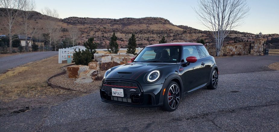A racing green 2022 Mini Cooper JCW hot hatch shot from the front 3/4 at dusk in the Rockies