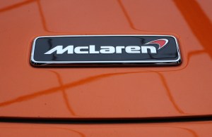 The McLaren logo on the hood of an orange 720S coupe in 2018