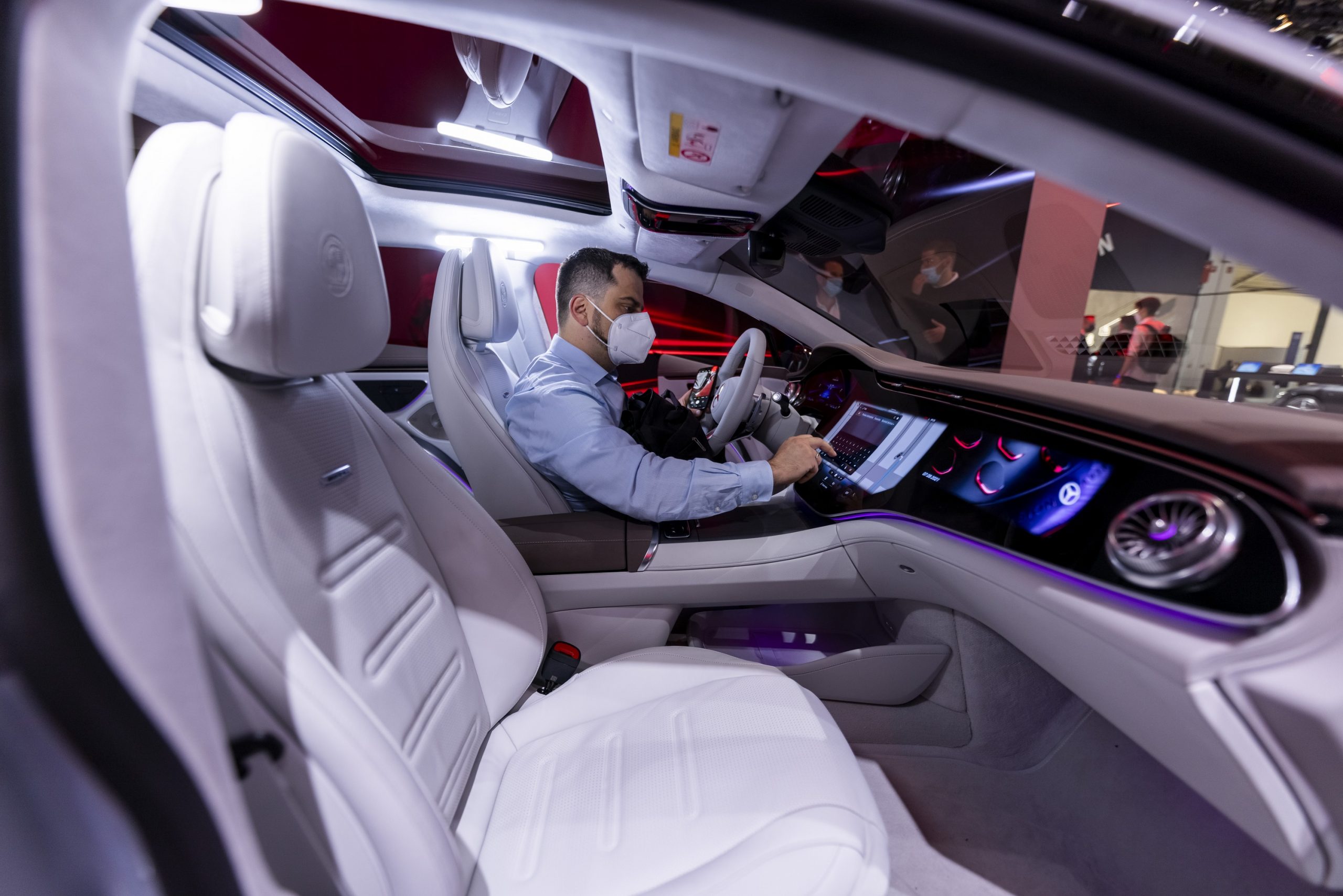 A man interacts with the infotainment on a Mercedes-Benz EQS EV sedan