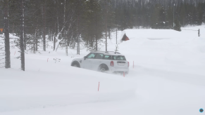A white Mini Countryman drives through the snow to test out all-wheel drive vs. winter tires.