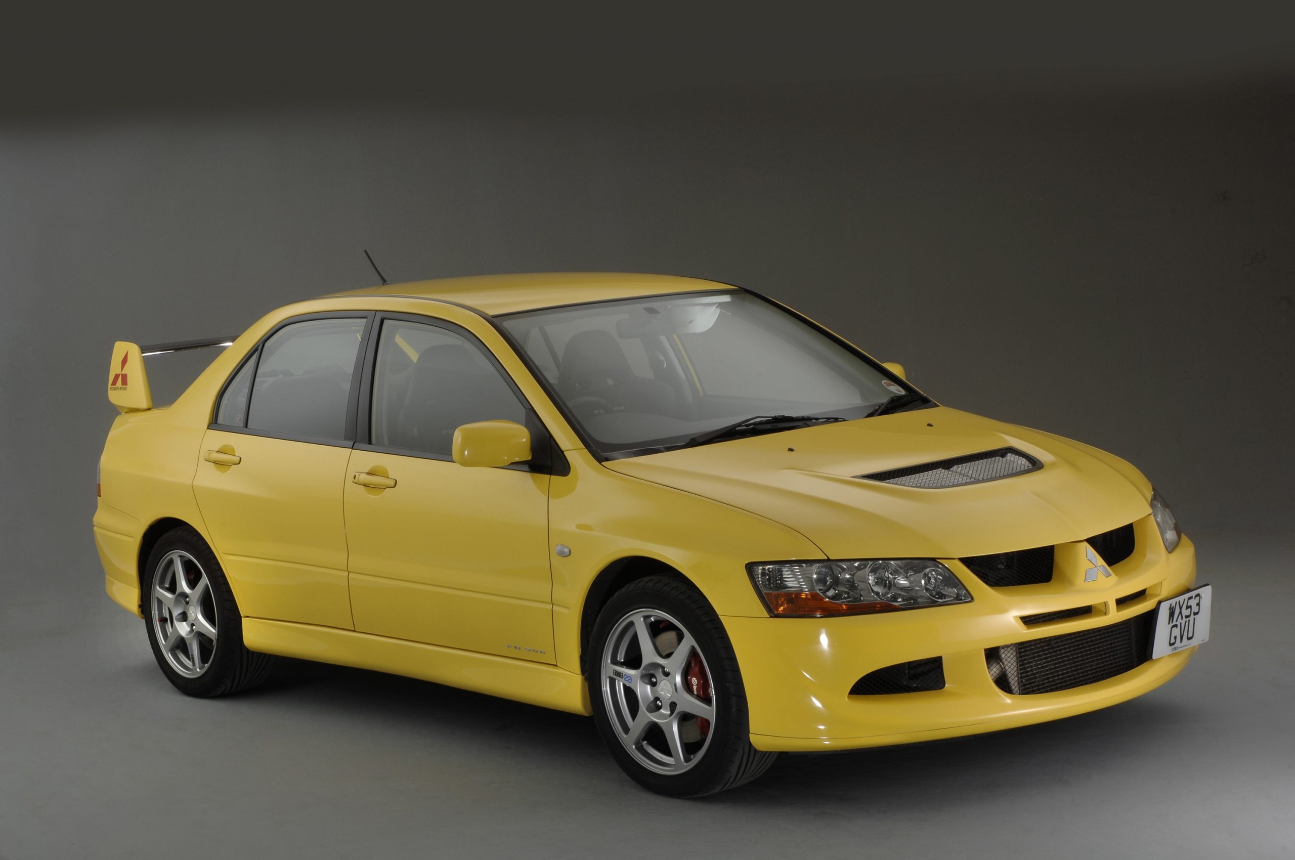 A yellow Mitsubishi Lancer Evolution shot from the front 3/4 in a photo booth