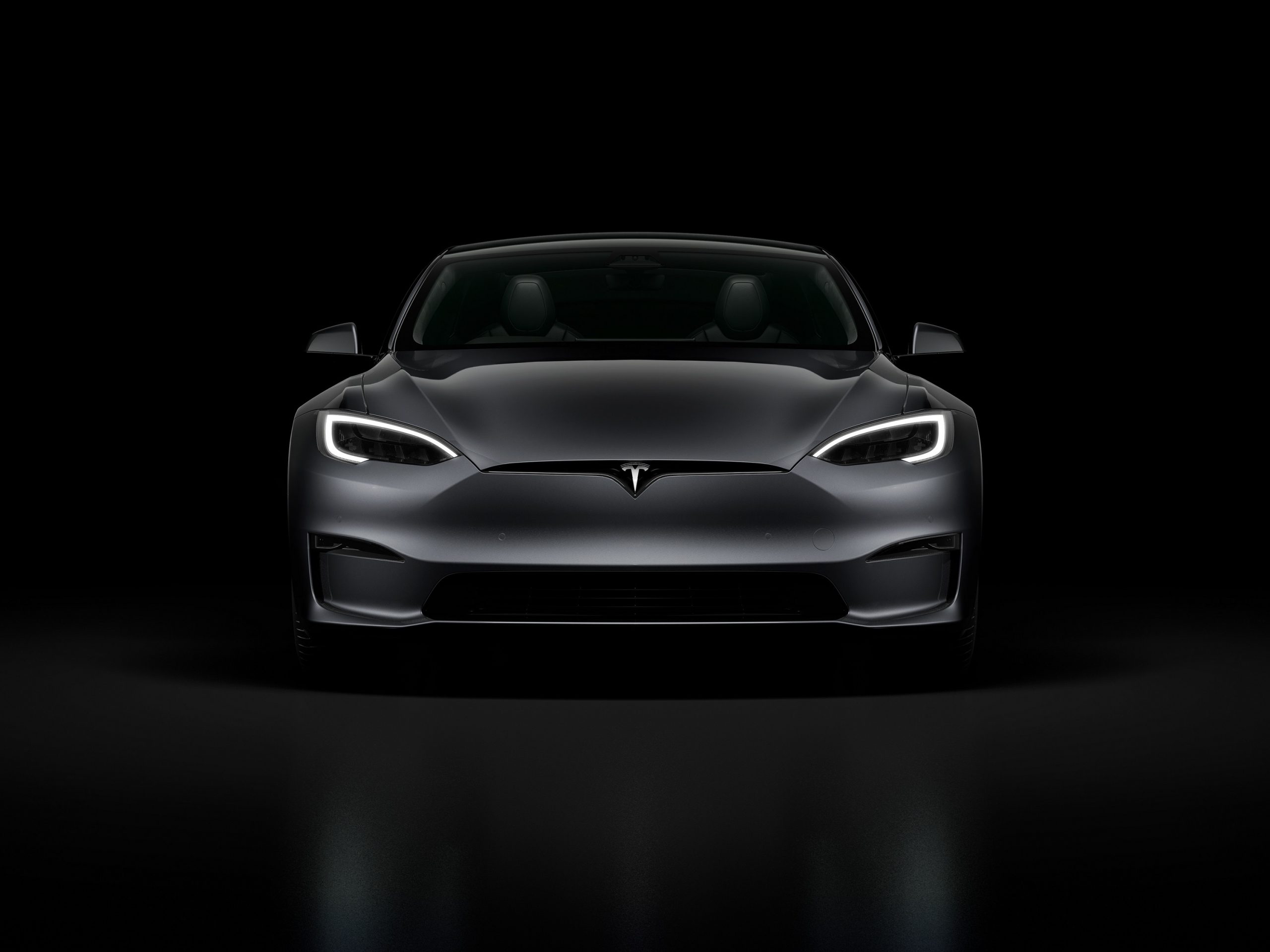 A grey 2022 Tesla Model S Plaid surrounded by shadow in a photo booth