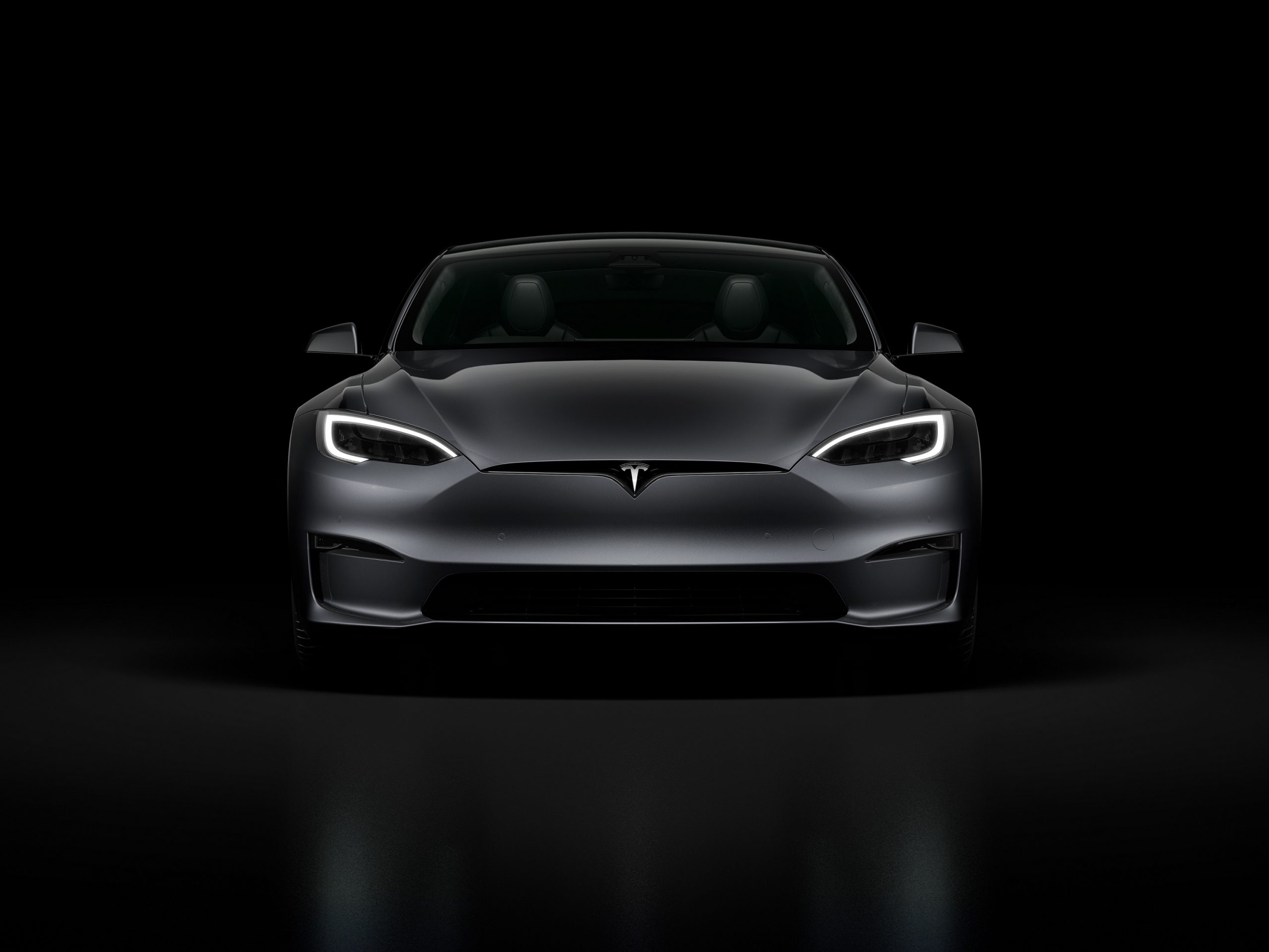A grey 2022 Tesla Model S Plaid surrounded by shadow in a photo booth