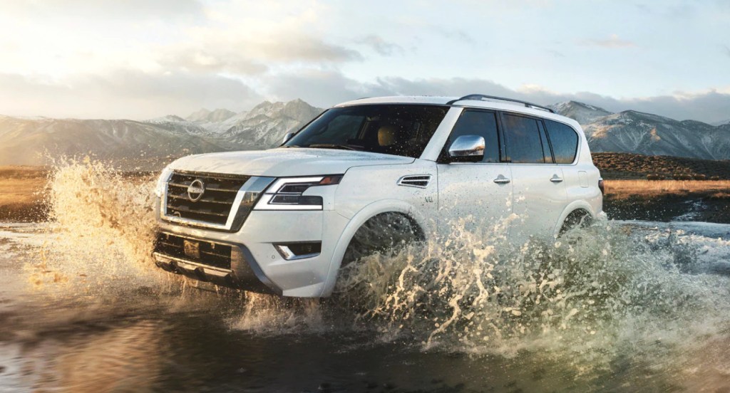 A white 2022 Nissan Armada is driving through shallow water. 