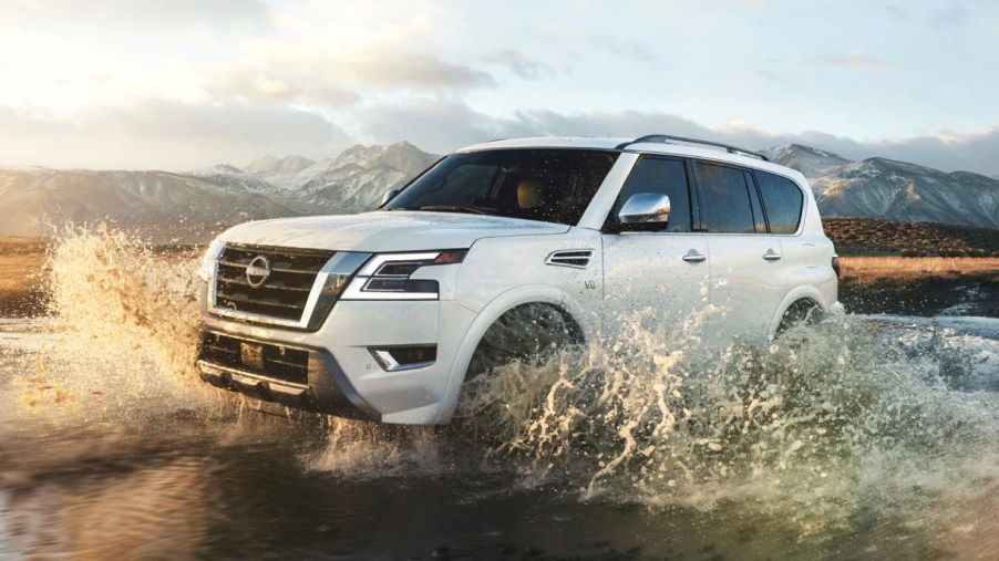 A white 2022 Nissan Armada is driving through shallow water.