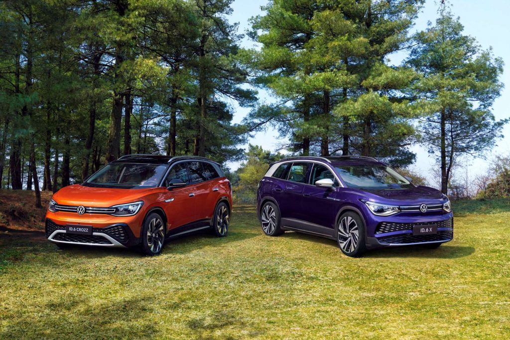 Orange and purple 2022 Volkswagen ID.6 electric SUVs parked next to a forest