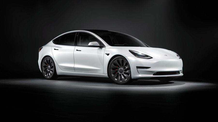 Passenger's side view of white 2022 Tesla Model 3, a car that has high gas mileage and fast acceleration