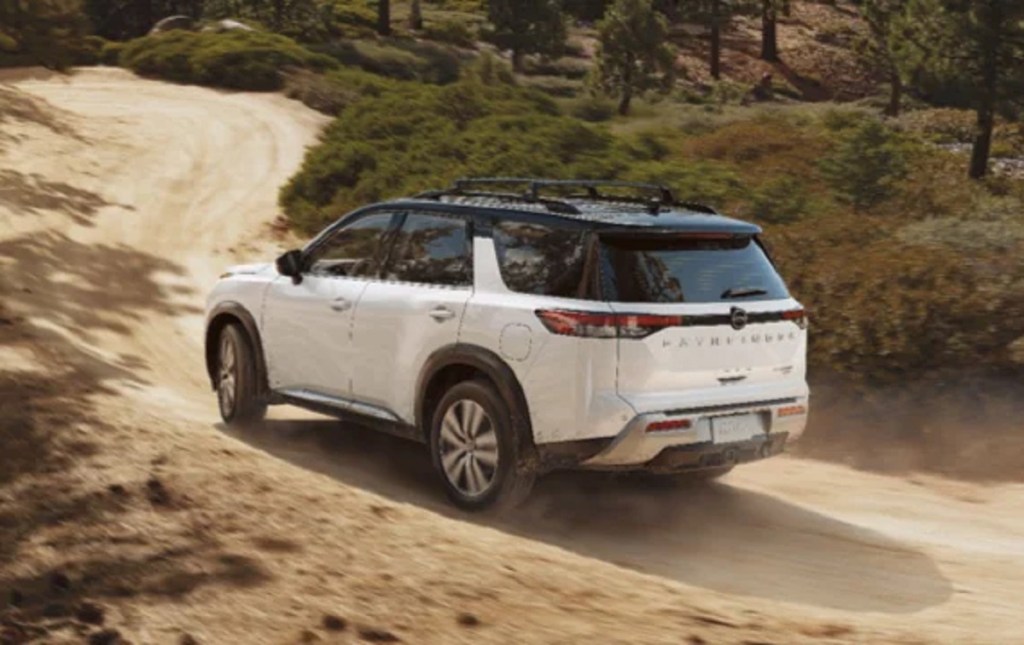A white 2022 Nissan Pathfinder driving down a dirt road.