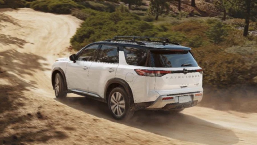 A white 2022 Nissan Pathfinder driving down a dirt road.