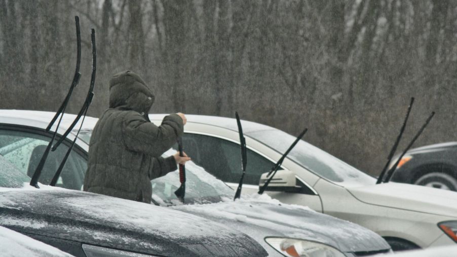 Person scraping ice off of a car windshield