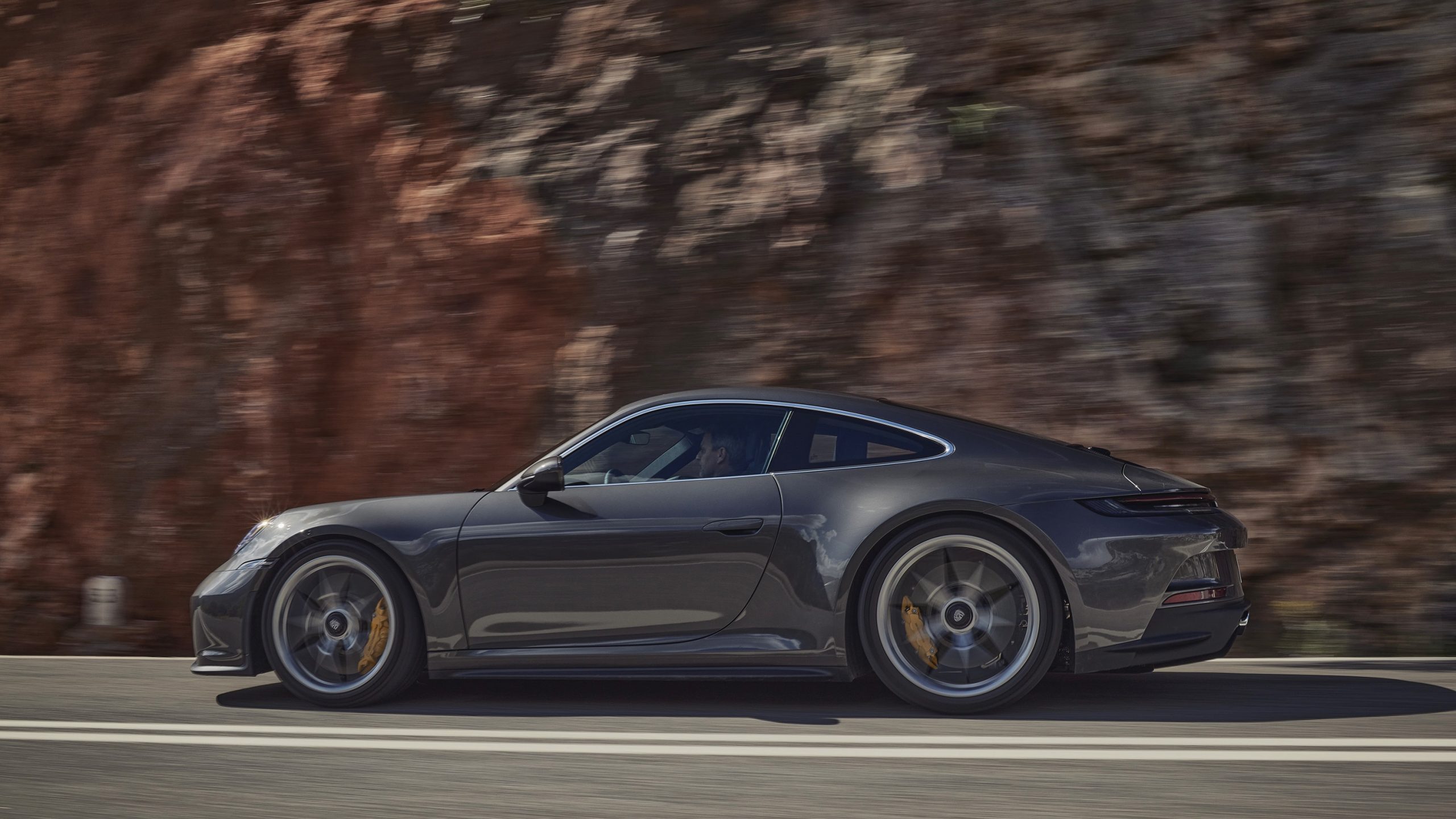 A grey Porsche 911 GT3 Touring shot in profile on a canyon road