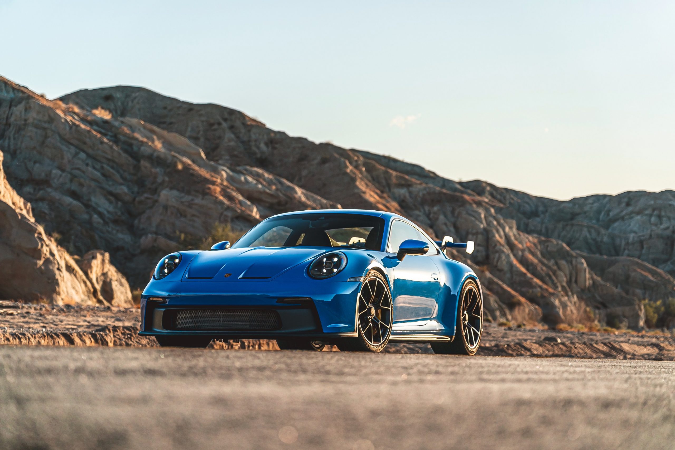 A Shark Blue 2022 Porsche 911 GT3 sports car shot from the front 3/4 in the Angeles forest