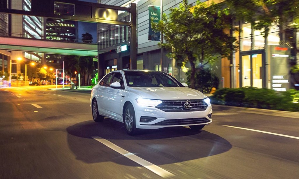 Pure White 2022 Volkswagen Jetta driving on a city street at night