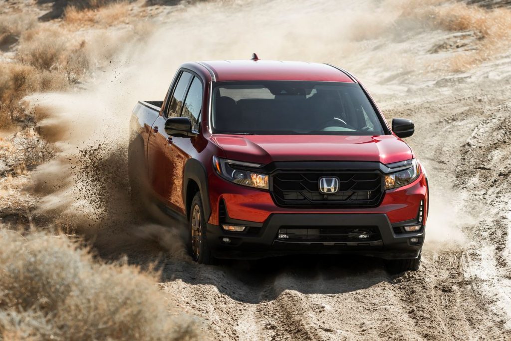 Red 2022 Honda Ridgeline driving on a dirt road, with a Consumer Reports reliability rating of 4 out of 5