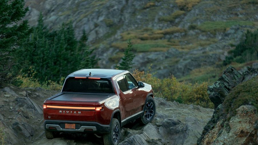 Red Canyon 2022 Rivian R1T parked on a rocky cliff, showing off its advantage over other EV trucks